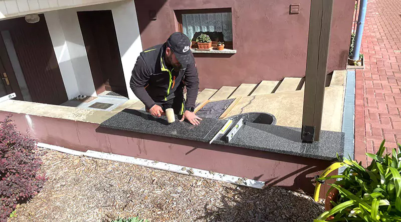 Ein Mann befestigt große Steinplatten auf einer Mauer