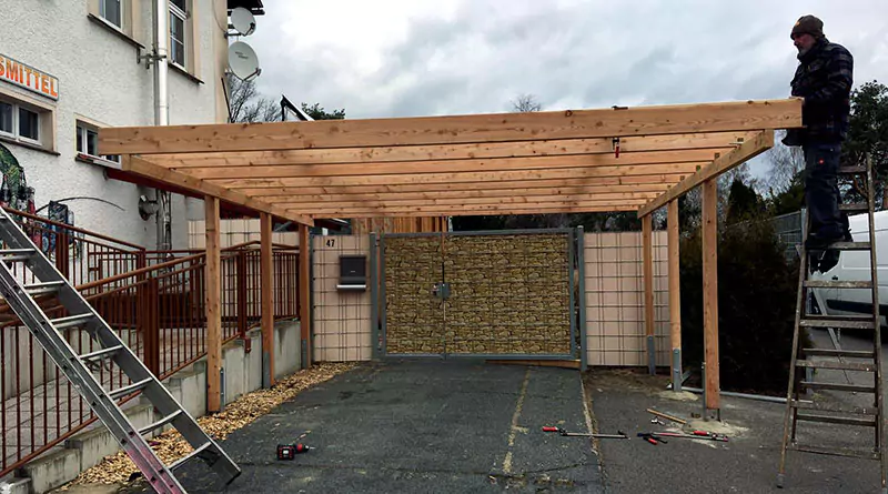 Ein Carport aus Holz wird über einem Parkplatz gebaut