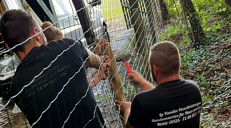 Ein Wildzaun wird von mehreren Personen aufgebaut